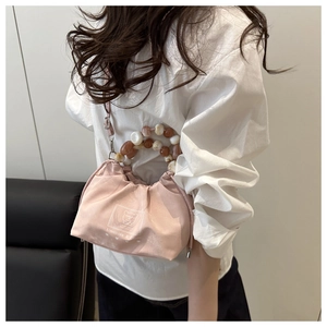 Close-up of pink pleated bucket bag with decorative amber and pearl bead handle