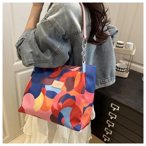 Detail of colorful abstract tote bag with pink leather strap and metal chain links