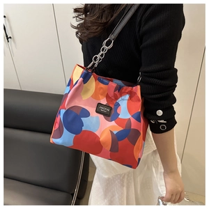 Detail of colorful geometric canvas tote with chain strap and leather branding label