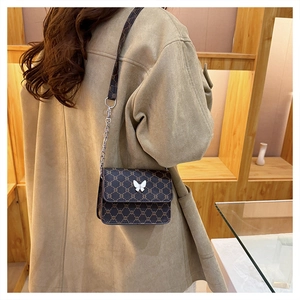 Detail of vintage square crossbody bag featuring monogram pattern and white butterfly charm