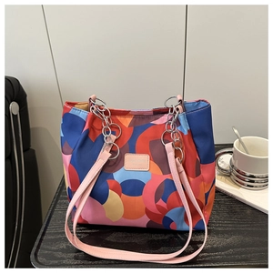 Detail of multi-color geometric print tote bag with chain strap on a black table