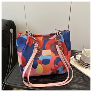 Detail of colorful geometric patchwork bag with silver chain and pink shoulder strap