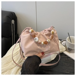 Detail of pink pleated bucket bag with acrylic bead handle and heart branding logo