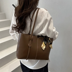 Large dark brown leather tote bag with white stitching and floral scarf on a model