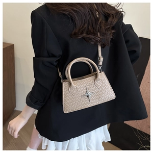 Beige faux crocodile skin handbag with silver star detail worn by model on shoulder