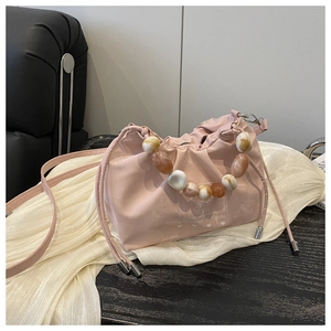 Detail of light pink bucket bag with colorful marble bead handle and silk texture