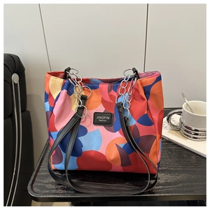 Detail of colorful abstract patchwork tote bag with chain strap on wooden table
