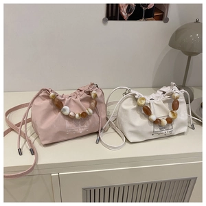 Detail of drawstring bucket bags with amber beaded handles and branding in soft colors