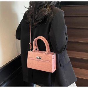Detailed view of pink crocodile texture shoulder bag with metallic clasp and handle