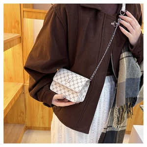 Detailed view of cream crossbody bag with vintage pattern and metal butterfly clasp