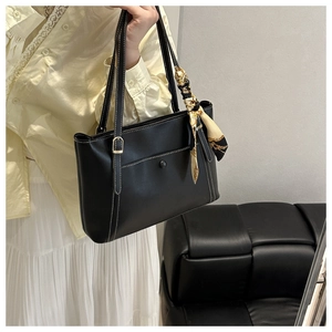 Detail of black faux leather tote bag with white stitching and decorative silk scarf wrap