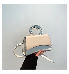 Detail of color-block handbag showing unique curved base and silver organic handle