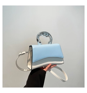 Detail of blue and white square handbag featuring unique silver liquid metal handle