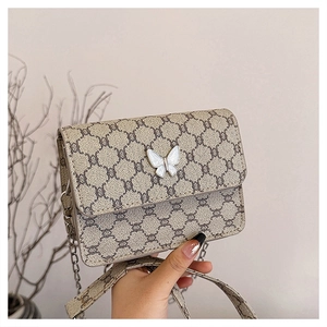Close-up of retro square crossbody bag featuring monogram pattern and butterfly metal clasp