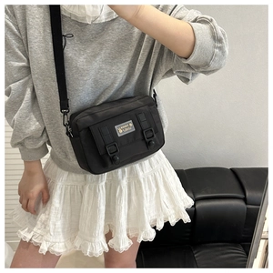 On-body view of a black nylon square crossbody bag with adjustable shoulder strap