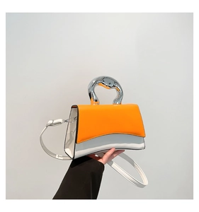 Detail of a color-block handbag with orange leather, white base and silver metal handle