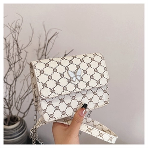 Detail of crossbody bag featuring monogram pattern and a decorative white butterfly clasp