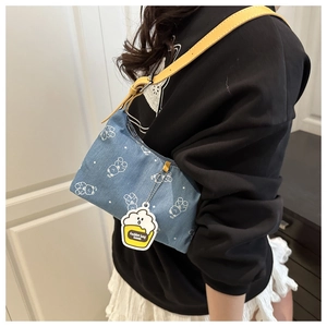 Détail du sac bandoulière en denim bleu clair avec imprimés ours blancs et breloque cupcake