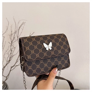 Detail of vintage brown crossbody bag with pearl butterfly buckle and silver chain strap