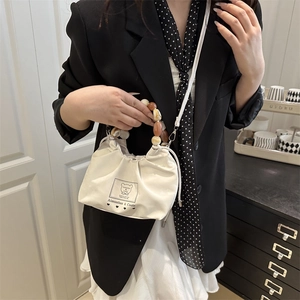 Chic white canvas bucket bag with colorful beaded handle and cartoon bear patch