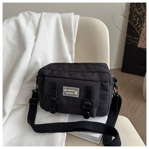 Detail van de zwarte utility crossbody tas met duurzame nylon textuur en verstelbare riemen