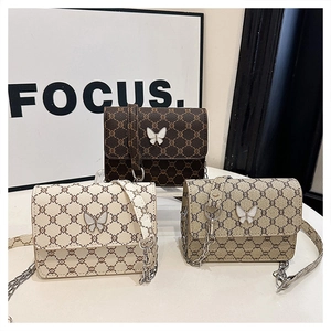 Detailed view of square crossbody bags with vintage patterns and butterfly emblem