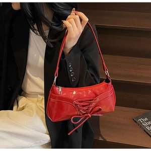 Détail du sac à bandoulière rouge avec design de nœud à lacets et cuir verni brillant