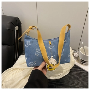 Détail du sac carré en denim bleu avec bandoulière jaune et motif d'ours cartoon