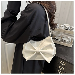 Detail of white PU leather shoulder bag with oversized bow on a model, chic summer style