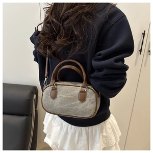 Detail of grey canvas pillow bag with brown leather handles worn by a model