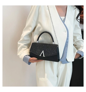Detail of black glitter crossbody bag with silver V-shaped buckle and chain strap
