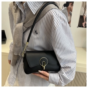 Detail of black leather underarm bag with gold circular clasp and chain shoulder strap