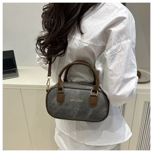 Detail of grey barrel bag showing premium leather handles and fashion logo on the side