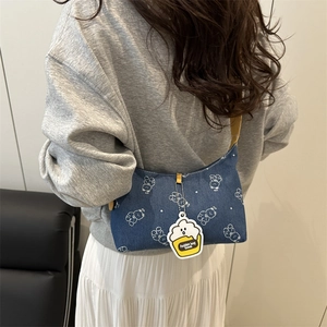 Sac sous le bras en denim bleu avec imprimés ours blancs et pendentif jaune sur un modèle