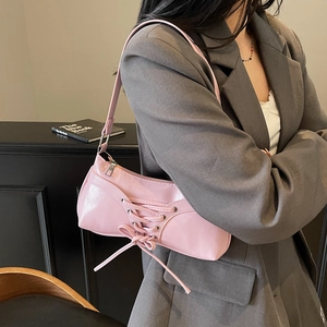 Sac baguette rose en similicuir avec détail de laçage porté par un mannequin en costume