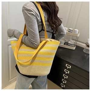 Vue latérale d'un grand sac cabas en paille à rayures jaunes porté par un mannequin