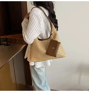 Detail of woven straw tote bag with brown leather strap and small side pouch