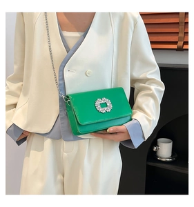 Detailed view of neon green mini crossbody bag with crystal buckle on white suit