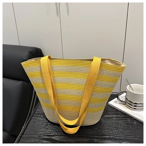 Détail d'un sac cabas en paille rayé jaune et beige avec larges bandoulières en toile
