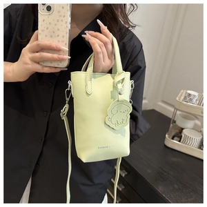 Close-up of mint green vertical mini bucket bag with cute dog charm and silver lettering