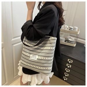 Detail of black and white striped canvas tote bag with fashion patch and wide strap