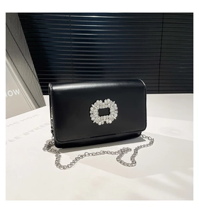 Detailed close-up of a black leather crossbody bag with a sparkling crystal buckle and chain