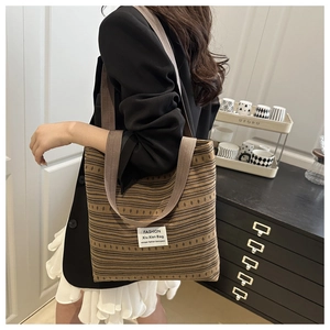 Detail of bohemian striped woven tote bag featuring durable brown straps and fabric patch