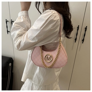 Detail of pink half-moon bag with golden M logo and chain strap on a white floral outfit