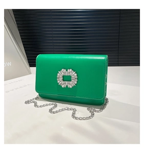 Detail of bright green leather crossbody bag featuring a sparkling crystal buckle and chain