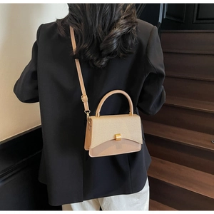 Sac bandoulière beige chic avec rabat texturé et fermoir doré porté par un modèle