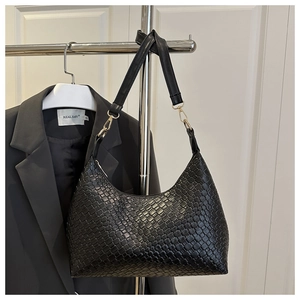 Detail of black woven leather hobo bag with gold hardware on a minimalist hanger