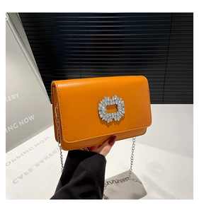 Detailed close-up of orange leather crossbody bag featuring a sparkling crystal buckle
