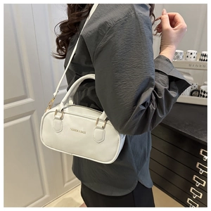 Close-up of a white minimalist shoulder bag with gold hardware and removable strap