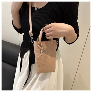 Detail of pink mini square crossbody bag with cute dog charm and adjustable shoulder strap